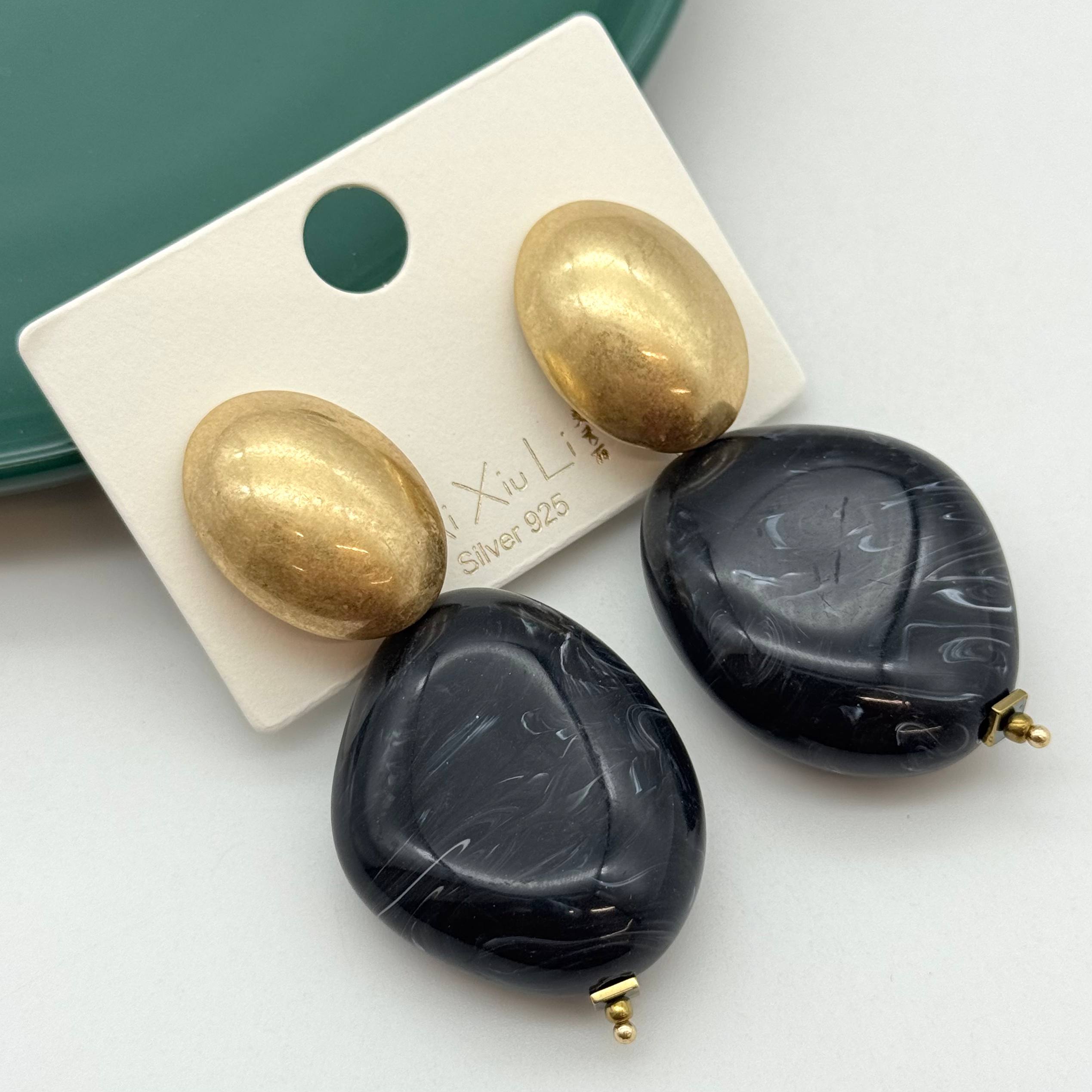 گوشواره بدلیجات استیل آویز با پلاک طلایی بیضی و سنگ رزین مشکی رگهدار