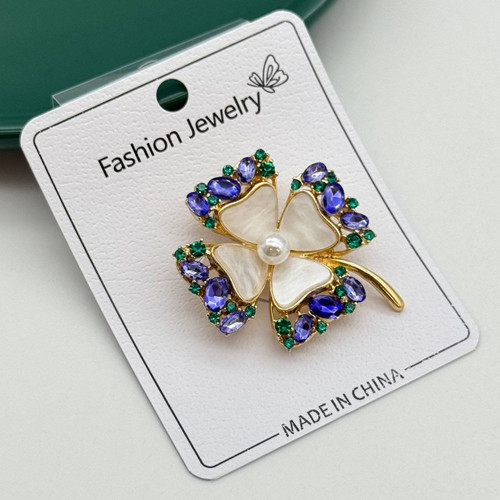 گل سینه طلایی طرح گل چهارپر با نگینهای آبی و سبز و مرکز مرواریدی