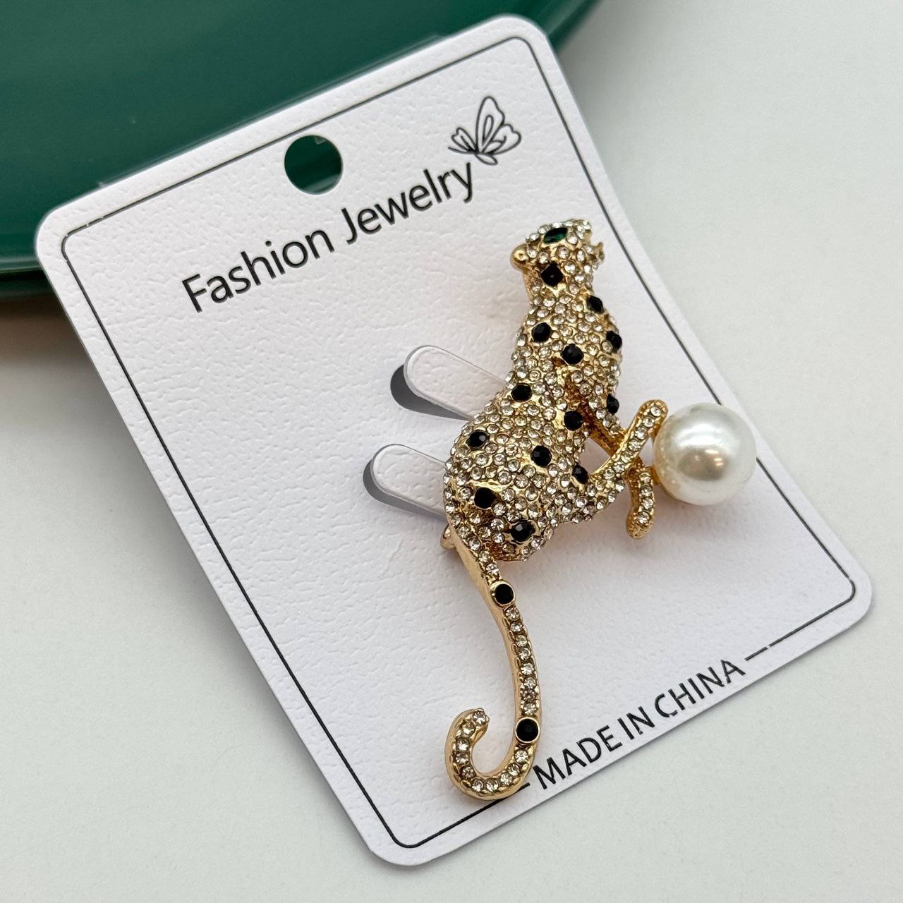 گل سینه طلایی طرح پلنگ با نگینهای کریستالی سفید و مشکی و مروارید بزرگ سفید.