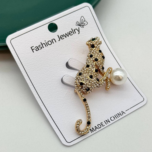 گل سینه طلایی طرح پلنگ با نگینهای کریستالی سفید و مشکی و مروارید بزرگ سفید.