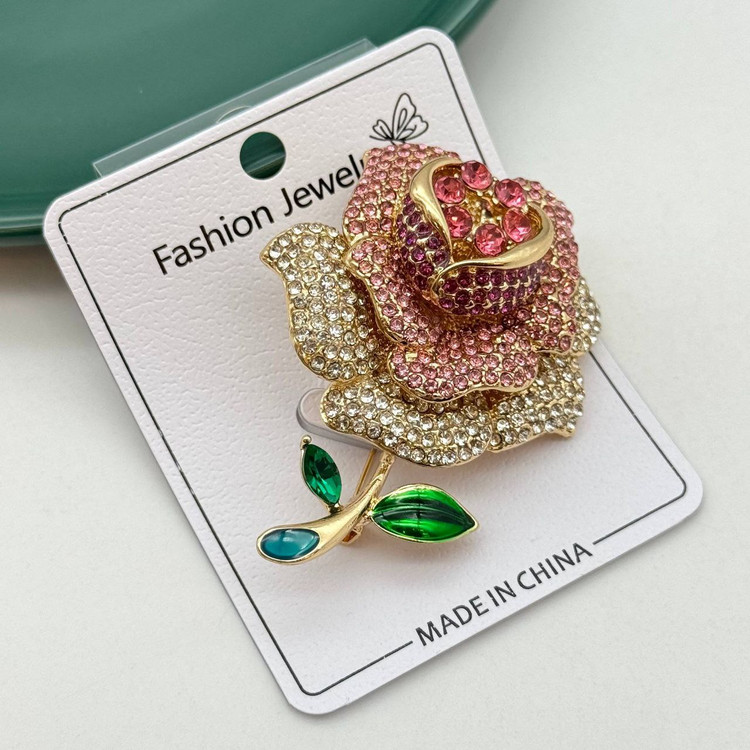 گل سینه طلایی طرح گل رز با نگینهای صورتی و سفید و برگهای سبز