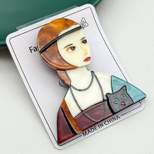 گل سینه رزینی طرح نیمتنه زن با کلاه قهوهای، گردنبند و گربه سیاه کوچک روی شانه.