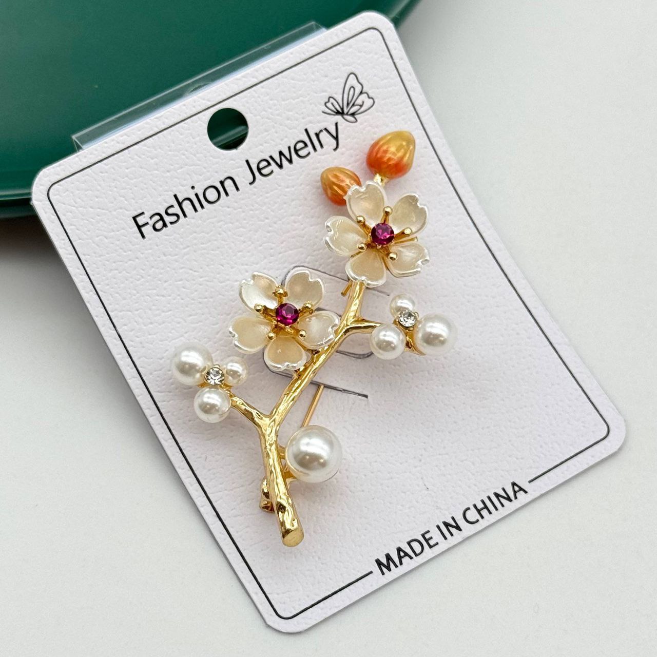 گل سینه طلایی طرح شاخه درخت با شکوفههای سفید، نگین قرمز و مروارید