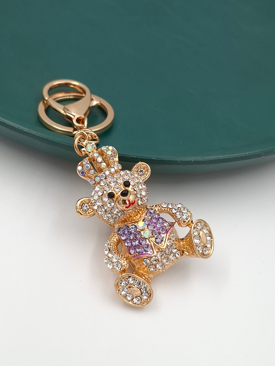 جاکلیدی طلایی طرح خرس تدی نگیندار با تاج پادشاهی و نگینهای بنفش.