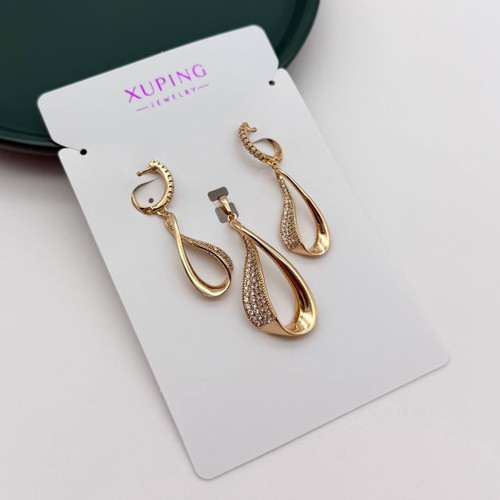تصویر استودیویی از نیمست زنانه ژوپینگ (XUPING) مدل آویز اشک مدرن و پیچخورده ، شامل یک جفت گوشواره و یک گردنبند، با نگینهای ریز زیرکونیا روی کارت مقوایی برند ژوپینگ.