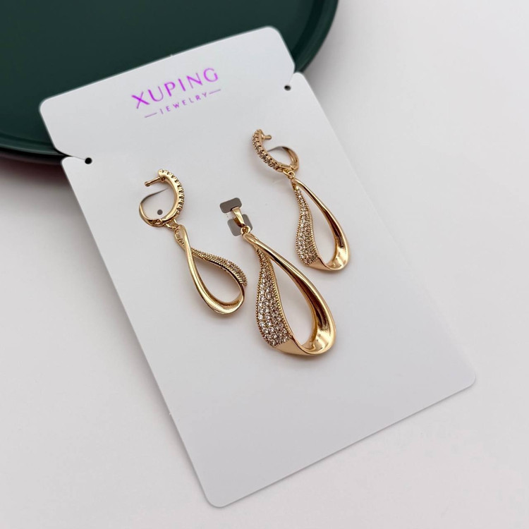 تصویر استودیویی از نیمست زنانه ژوپینگ (XUPING) مدل آویز اشک مدرن و پیچخورده ، شامل یک جفت گوشواره و یک گردنبند، با نگینهای ریز زیرکونیا روی کارت مقوایی برند ژوپینگ.